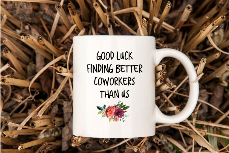 Peut inclure: Une tasse &agrave; caf&eacute; en c&eacute;ramique blanche avec du texte noir qui dit "Bonne chance pour trouver de meilleurs coll&egrave;gues que nous". La tasse a un motif floral avec des fleurs roses, rouges et vertes.