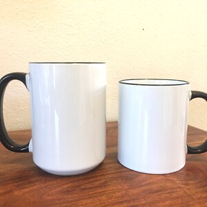 Puede incluir: Dos tazas de cer&aacute;mica blanca con bordes y asas negros. La taza de la izquierda es m&aacute;s alta que la taza de la derecha.