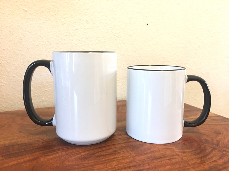 Puede incluir: Dos tazas de cer&aacute;mica blanca con bordes y asas negros. La taza de la izquierda es m&aacute;s alta que la taza de la derecha.