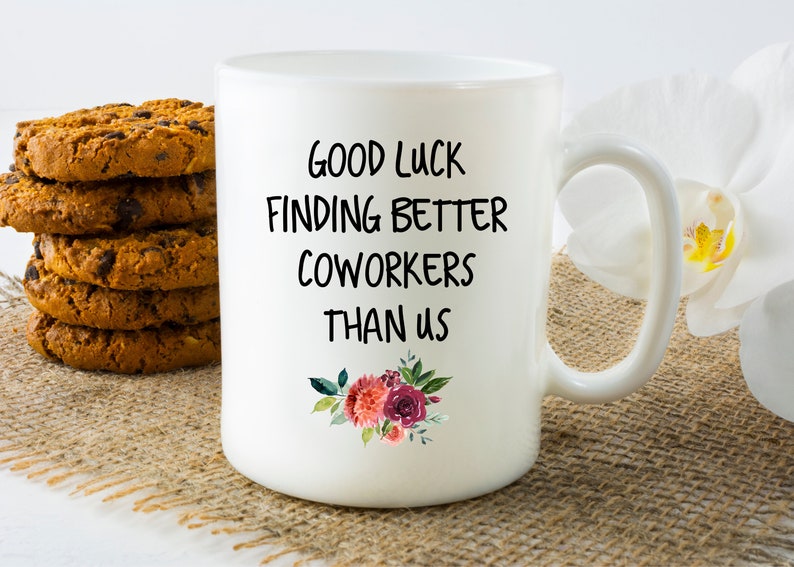 Peut inclure: Une tasse &agrave; caf&eacute; en c&eacute;ramique blanche avec du texte noir qui dit "Bonne chance pour trouver de meilleurs coll&egrave;gues que nous". Le texte est entour&eacute; d'un motif floral avec des fleurs roses et rouges.