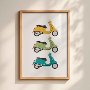 May include: A framed print showing three scooters in yellow, green, and teal. Each scooter has a black seat and white tyres. The artwork is set against a white background and framed in light wood, suitable for a home or office.