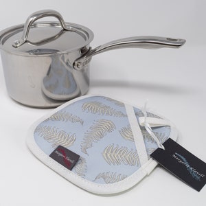 May include: A stainless steel saucepan with a lid and a matching pot holder. The pot holder is blue with a white border and a fern pattern. The pot holder has a tag that says "Margaret Clavell".