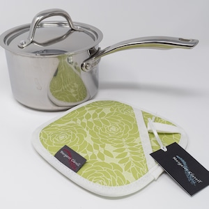 May include: A stainless steel saucepan with a lid and a green floral pot holder with a white border. The pot holder has a tag that says "Margaret Clavell".