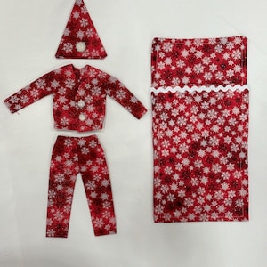 May include: Red and white pajama set with a snowflake pattern, including a hat, jacket, pants, and a sleeping bag.