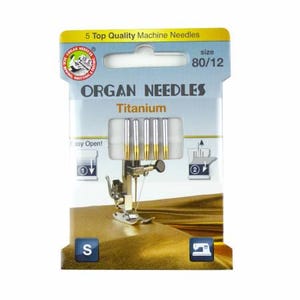 May include: A pack of 5 Organ Needles Titanium sewing machine needles in size 80/12. The needles are silver with gold tips and are packaged in a clear plastic container with a white label. The label has the Organ Needles logo and the text "Titanium" and "Easy Open!" printed on it.