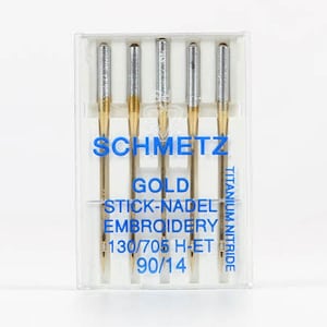 May include: A pack of five gold titanium nitride embroidery needles in a clear plastic case. The needles are labeled "Schmetz Gold Stick-Nadel Embroidery 130/705 H-ET 90/14".