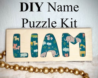 May include: DIY Name Puzzle Kit with the name LIAM spelled out in wooden letters. Each letter is decorated with a teal blue background and a pattern of colorful animals. The letters are on a wooden base.