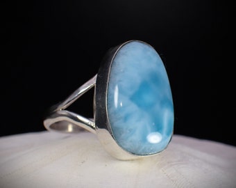 May include: A silver ring featuring a large oval blue and white gemstone. The gemstone has a cloudy, marbled appearance.