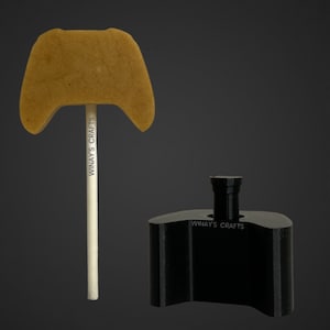 Könnte beinhalten: Ein brauner Schokoladen-Lolli in Form eines Videospiel-Controllers auf einem weißen Stiel mit dem Text "WINAY'S CRAFTS" auf dem Stiel. Eine schwarze Plastikform in Form eines Videospiel-Controllers mit dem Text "WINAY'S CRAFTS" auf der Form.