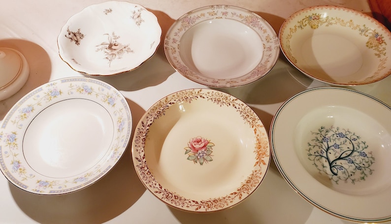 May include: Set of six white ceramic soup bowls with various floral patterns. The bowls have gold trim and are ideal for serving soup, salad, or dessert.