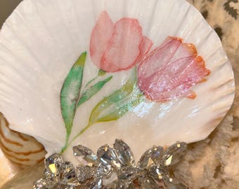 Concha marina decorada con tulipanes y joyas añadidas mediante la técnica del decoupage.