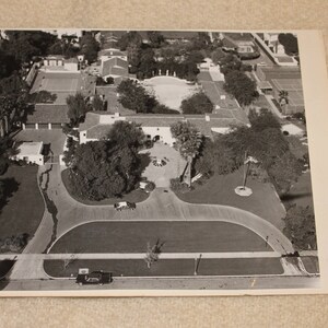 May include: An aerial black and white photograph of a large estate with a sprawling lawn, multiple buildings, and a tennis court. The image is signed "Arthur K. Bournand".