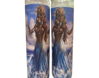May include: Two glass candle jars with blue and white labels featuring an image of a woman with a crown of seashells and a blue dress standing in the ocean. The text "Yemoja" is printed on the labels.
