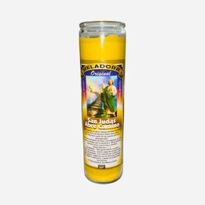 May include: A tall, yellow candle in a clear glass jar. The label features an image of a saint and the text "San Judas Abre Camino". The candle is designed for religious or spiritual use.