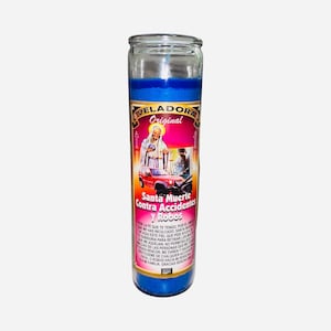 May include: A blue glass candle with a label featuring an illustration of a saint, a red car, and the text "Santa Muerte Contra Accidentes y Robos". The candle has a blue wax interior and is designed for religious or spiritual use.