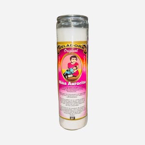 May include: A white candle in a clear glass jar. The label features the text "VELADORA Original" and an illustration of a child holding another child. The label also includes the text "Niña Aurorita" in pink and gold lettering.