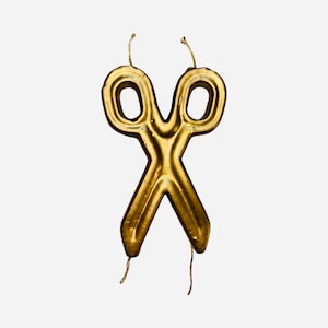 May include: Gold-colored scissors shaped birthday candle with a wick on each end.