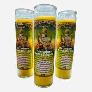 May include: Three yellow candles with the words "Veladora Original" and "Herradura Venta Rapida" printed on them. The candles are decorated with images of a horseshoe, money, and a cash register.