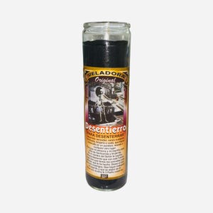 May include: A tall glass candle with black wax and a label featuring the text "VELADORA Original Desentierro PARA DESENTERRAR" and an illustration of a skeleton. The candle is designed for spiritual practices.