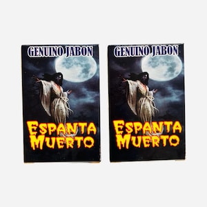 May include: Two rectangular soap boxes featuring the text GENUINO JABON and ESPANTA MUERTO. The design displays a figure in a long white robe standing against a dark, cloudy night sky with a large, bright full moon in the background.