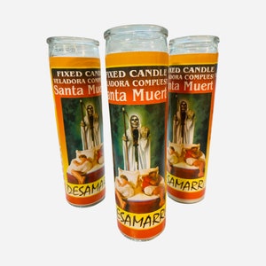 May include: Three glass candle jars with orange labels featuring an image of Santa Muerte, a skeletal figure in a white robe, holding a scythe. The labels also include the text "Fixed Candle", "Veladora Compuesta", and "Santa Muerte".