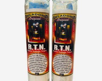 Könnte beinhalten: Zwei weiße Kerzen mit blauen Etiketten. Die Etiketten tragen die Worte "Veladora Original" und "R.T.N. Retira Trabajo Negro". Die Kerzen befinden sich in Glasbehältern.