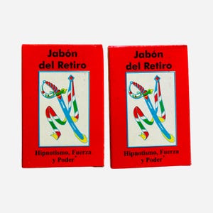 May include: Two rectangular red soap boxes labeled Jabón del Retiro. The center features a white square with a blue sword illustration and colorful ribbons. Below the graphic, the text reads Hipnotismo, Fuerza y Poder in black lettering.