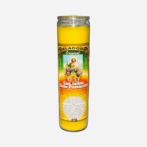 May include: A tall, cylindrical yellow candle in a clear glass jar. The label features the text "VELADORA Original" and "San Judas Siete Potencias" with an image of a saint. The candle is designed for religious or spiritual use.
