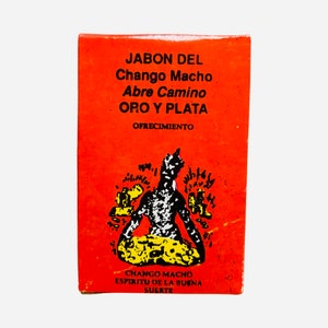 以下が含まれることがあります： 「JABON DEL Chango Macho Abre Camino ORO Y PLATA」の文字と人物のイラストが描かれたオレンジ色の箱。箱には「OFRECIMIENTO」と「CHANGO MACHO ESPIRITU DE LA BUENA SUERTE」の文字も含まれています。