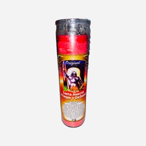 May include: A red candle with a clear glass container. The candle has a label with the text "Original Santa Muerte Ataque y Defensa" and an image of a figure holding a weapon.