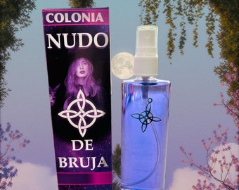 May include: A purple bottle of "Colonia Nudo De Bruja" natural spray with a white spray nozzle. The bottle has a black symbol on the front. The bottle is in front of a box with the same text and symbol. The box also has a picture of a woman with purple hair.