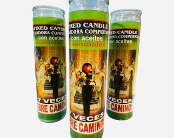 May include: Three green glass candle jars with white labels. The labels have text in Spanish that reads "FIXED CANDLE ELADORA COMPUESTA con aceites esenciales 7 VECES ABRE CAMINO". The candles have a green and white image of a couple standing on a staircase with a heart above them.