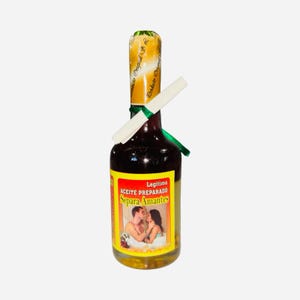 May include: A glass bottle filled with a dark liquid, featuring a yellow and red label with the text "ACEITE PREPARADO Separa Amantes." The bottle is sealed with a gold foil top and a white paper scroll. A green ribbon is tied around the neck.