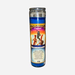 May include: A blue glass candle with a label that reads "VELADORA Original Desamarrador." The label features an illustration of a figure and text in Spanish. The candle is cylindrical and has a blue wax interior.