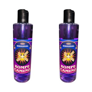 May include: Two purple bottles with a label that says "Original Rompe Camino" in a yellow, red, and black design. The label features a stylized image of crossed wooden sticks with the words "Sal y Romero" on each stick.