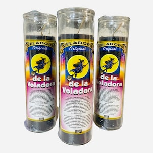 May include: Three black glass candles with a witch on a broomstick graphic and the text "VELADORA Original de la Voladora" on the label. The candles are wrapped in clear plastic.