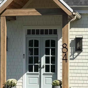 Large 12 inch black THIN MODERN house numbers 84 fastened on a post by the front door