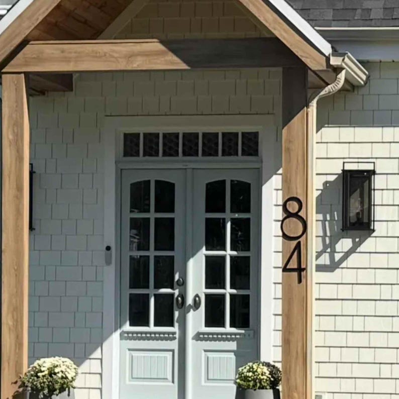 Large 12 inch black THIN MODERN house numbers 84 fastened on a post by the front door