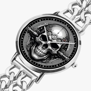 A silver wristwatch with a black face and a skull design. The skull is surrounded by gears and other mechanical elements. The watch has a silver chain link band.