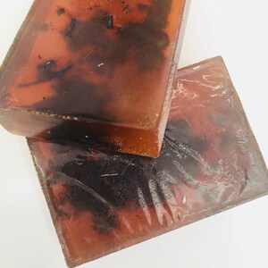 May include: Two bars of handmade soap with a brown and black marbled appearance. The soap is translucent and has a natural, earthy look.