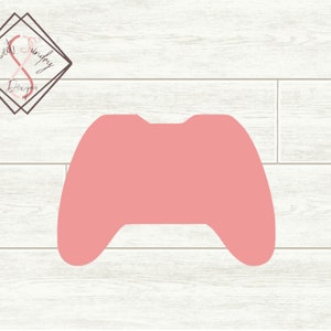 Może przedstawiać: Różowy plastikowy wykrój kontrolera do gier wideo. Kontroler ma prosty design bez przycisków ani szczegółów.