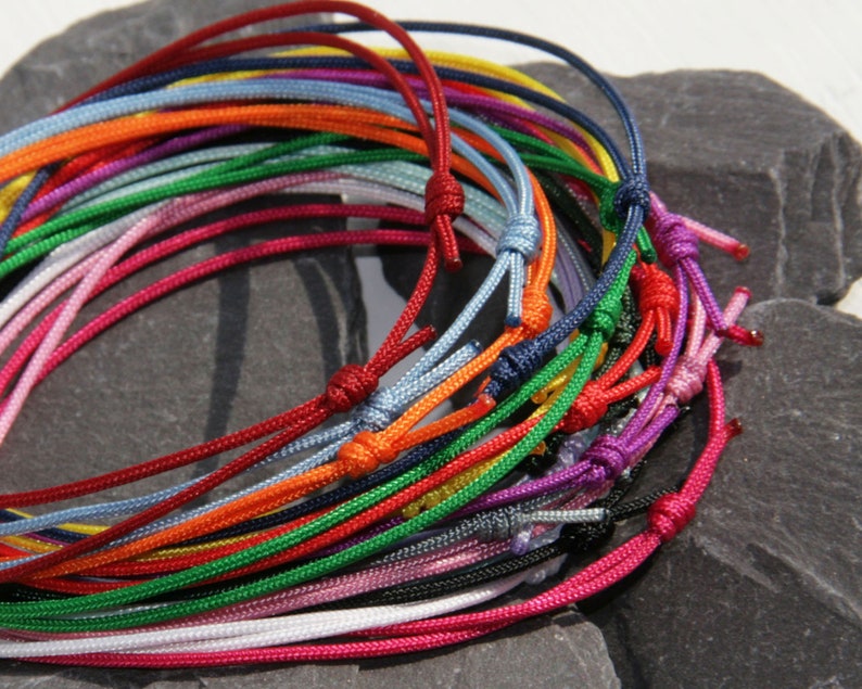 Pu&ograve; includere: Una collezione di cordini colorati legati insieme in un fascio. I cordini sono fatti di una variet&agrave; di materiali, tra cui cotone, nylon e pelle. I cordini sono di tutti i colori, tra cui rosso, blu, verde, giallo e arancione.