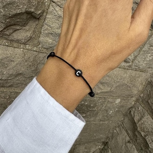 May include: A black elastic bracelet with a black bead featuring the letter "C" in white.