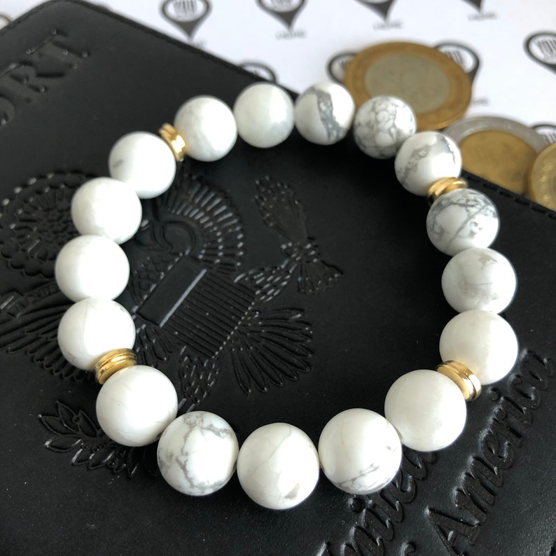 Peut inclure: Bracelet en perles d'howlite blanche avec des accents dor&eacute;s. Le bracelet est compos&eacute; de perles rondes et a un design simple.