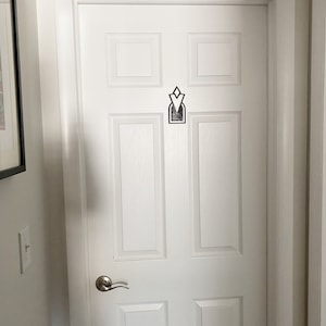 Pu&ograve; includere: Una porta bianca con una maniglia argentata e un design geometrico bianco e nero sul pannello centrale.