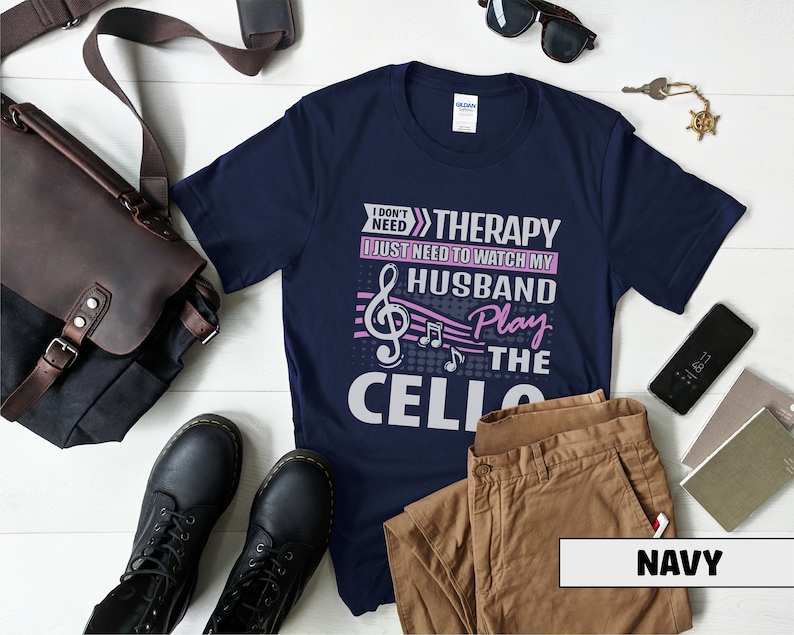 Pu&ograve; includere: Maglietta blu navy con una grafica bianca che dice "Non ho bisogno di terapia, ho solo bisogno di guardare mio marito suonare il violoncello". La grafica include una nota musicale e note musicali.