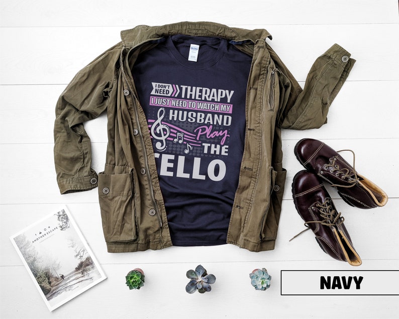 Pu&ograve; includere: Maglietta blu navy con un grafico di nota musicale e il testo "Non ho bisogno di terapia, ho solo bisogno di guardare mio marito suonare il violoncello".