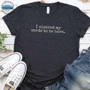 May include: A dark gray t-shirt with the text "I cleared my cards to be here." printed in white.