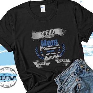 May include: Black t-shirt with a blue and white thin blue line design and the text "Proud Mom of a Brave Deputy Sheriff".
