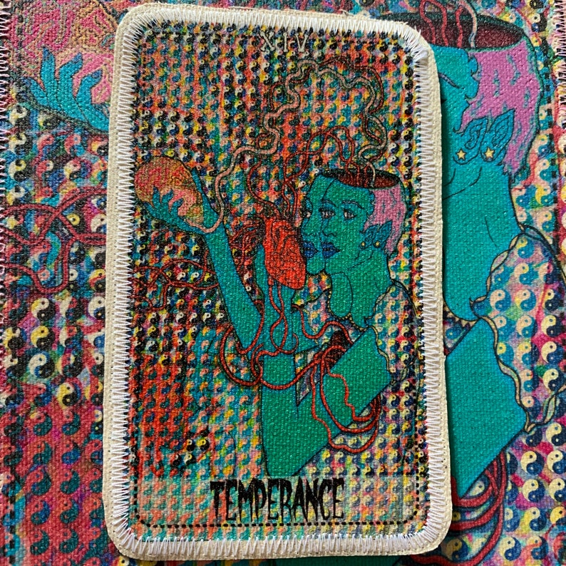 K&ouml;nnte beinhalten: Rechteckiger Aufn&auml;her mit der Illustration der Tarotkarte Temperance. Das Design zeigt eine t&uuml;rkisfarbene Figur mit zwei Gesichtern, die ein rotes Objekt h&auml;lt. Der Hintergrund ist ein farbenfrohes Muster mit dem Wort "TEMPERANCE" am unteren Rand.